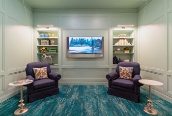 A room with two chairs and a TV on the wall.